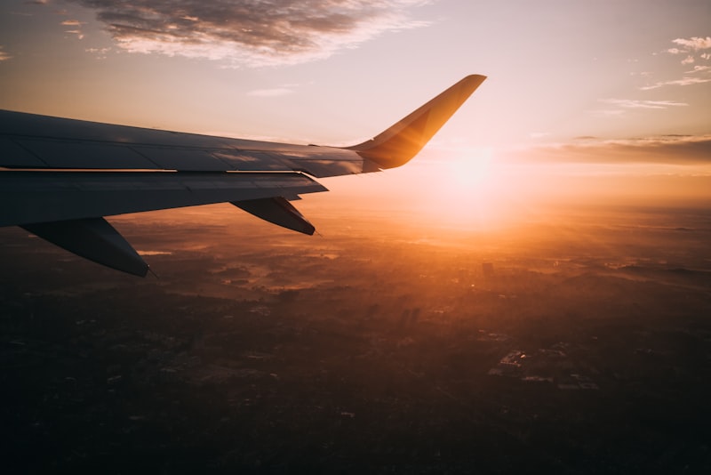 Beautiful airplane wing view against golden hour sunset clouds